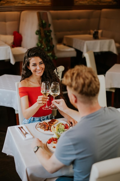 Giovani coppie che pranzano con vino bianco nel ristorante