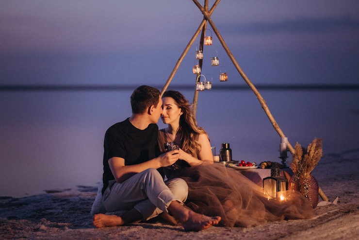 Photo young couple having a picnic on the beach of a pink lake