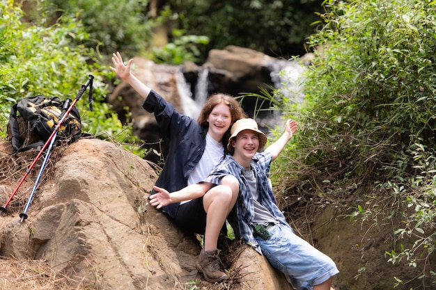 Young couple of hikers sitting on a rock and kissing