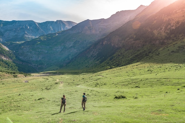 日没のディスカバリー旅行中に山の間の美しい谷でハイキングする若いカップル