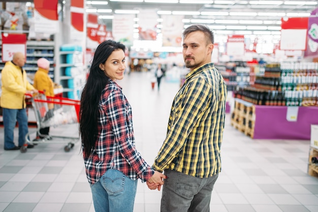 Young couple hold hands in supermarket
