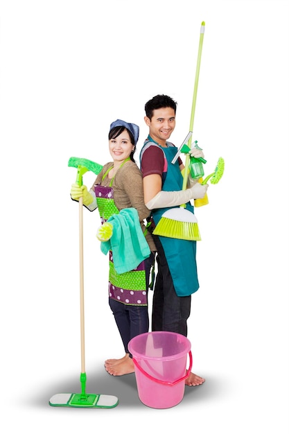 Young couple holding cleaning supplies on studio