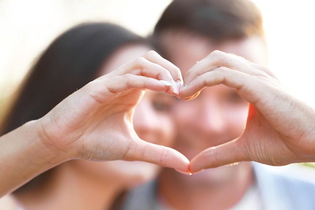 Young couple holding hands in shape of heart