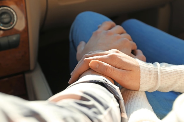 Young couple holding hands together in car