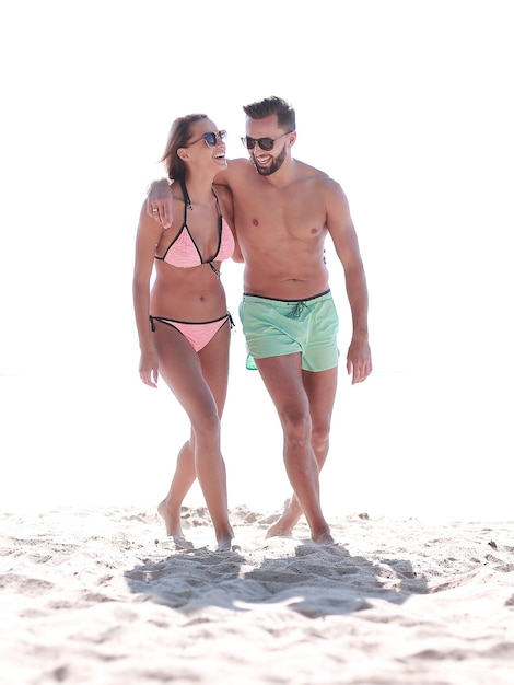 Young couple holding hands and walking on beach