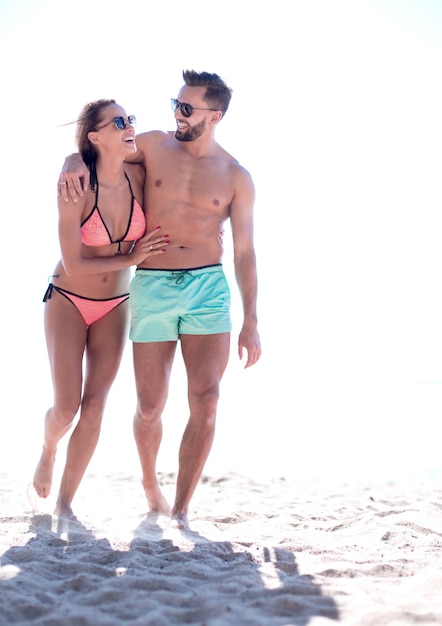 Young couple holding hands and walking on beach