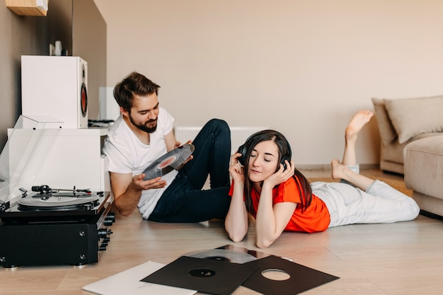 Young couple at home, listening to music on a vinyl player