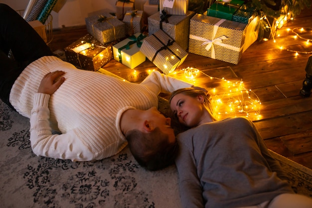 Young couple at home lying on the floor near Christmas presents