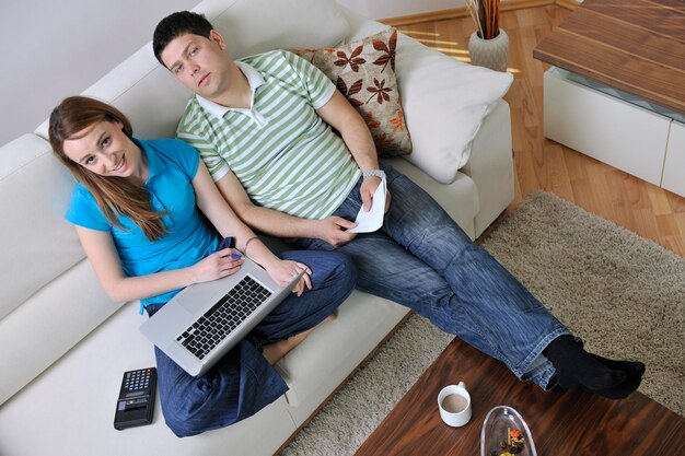 Young couple at home with modern livingroom indoor working on laptop on house finance and planing