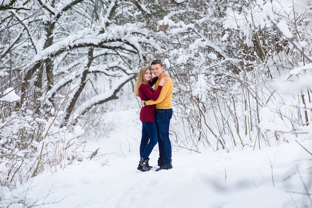 Young couple hug in winter forest