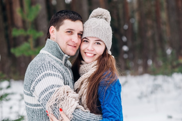 Young couple hugging and kissing in the forest in winter.