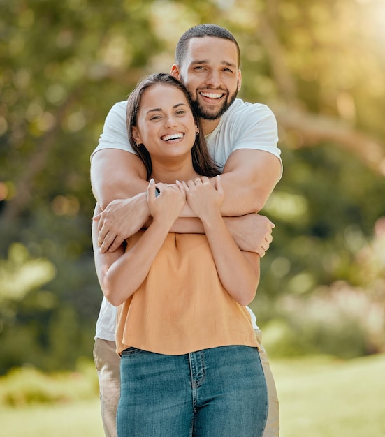 Young couple hugging in park garden and nature for love care and romantic date together outdoors in Colombia Portrait of smile laughing and relax couple in happy marriage and joyful relationship