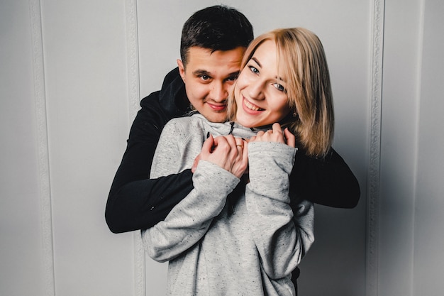 Young couple hugging and posing on a light background