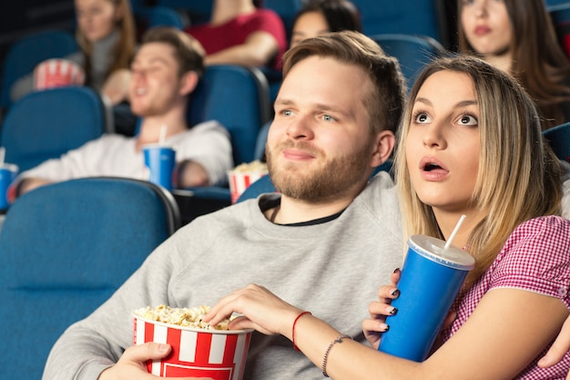 映画館で一緒に映画を見てハグする若いカップル