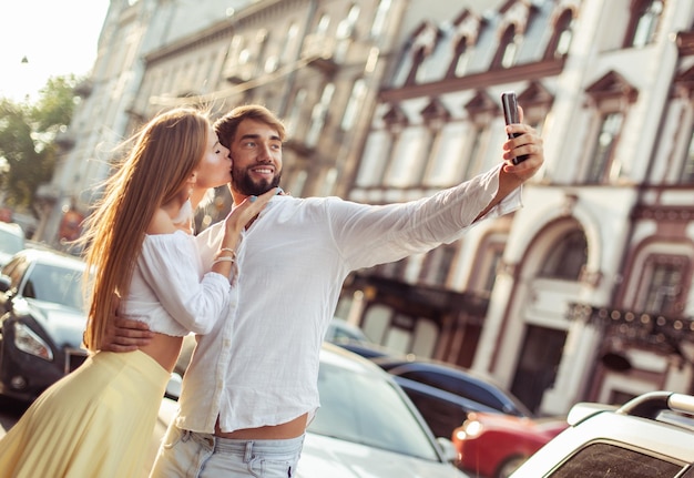 写真 若い恋人カップルは街でスマートフォンでセルフィーを撮りますロマンチックな愛のコンセプト