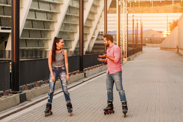 Young couple inline skating girl on rollerblades smiling cheerful mood and good impressions