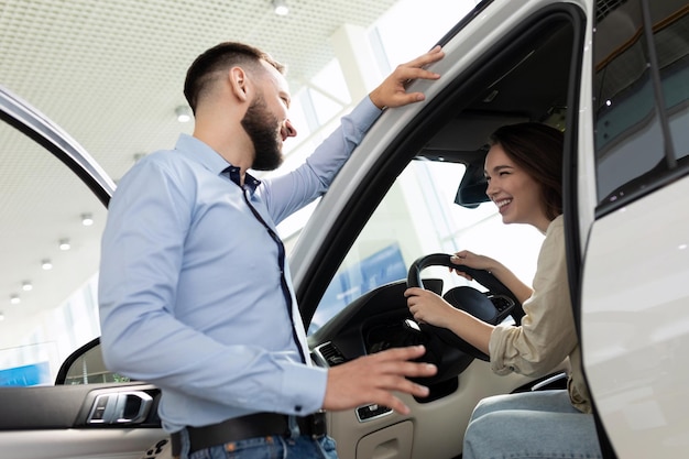 Foto una giovane coppia è determinata con l'acquisto di una nuova auto in una concessionaria di automobili