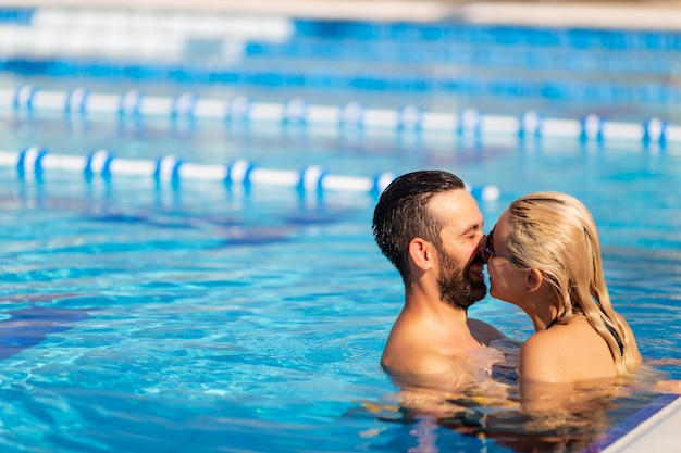 Young couple is swimming in the pool and laughing