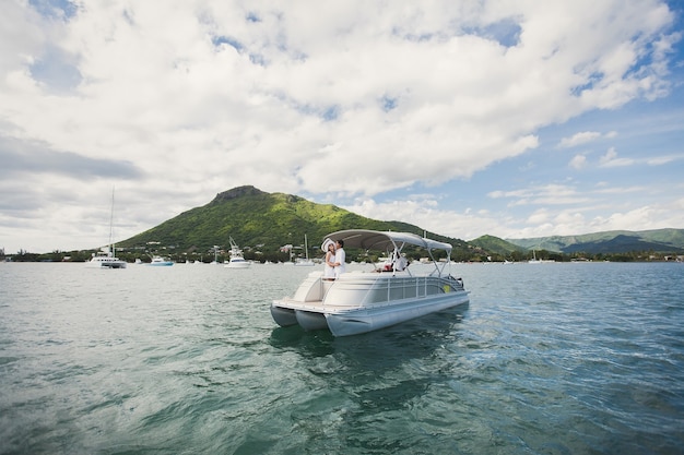 Young couple is traveling on a yacht in the indian ocean. on the bow of the boat, a loving family embraces