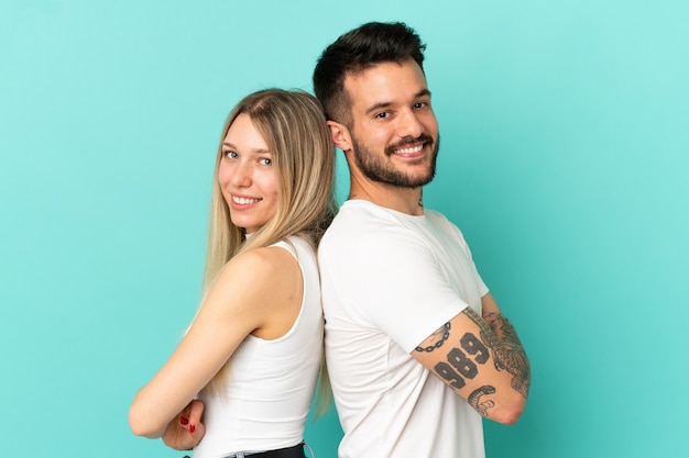 Young couple over isolated blue background keeping arms crossed