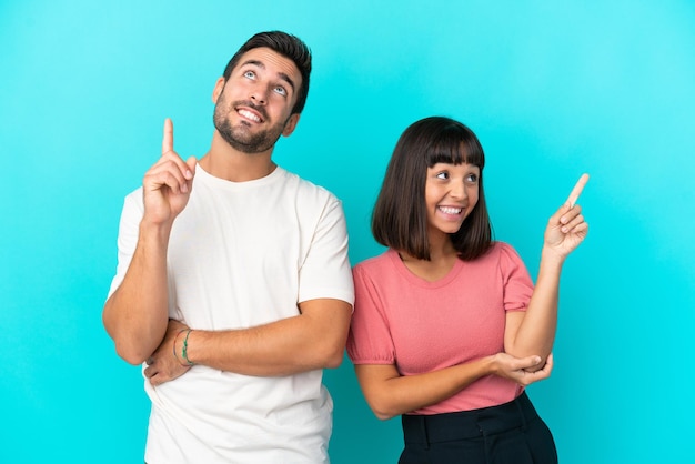 Young couple isolated on blue background pointing a great idea and looking up