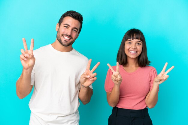 Giovani coppie isolate su fondo blu che sorridono e che mostrano il segno di vittoria con entrambe le mani