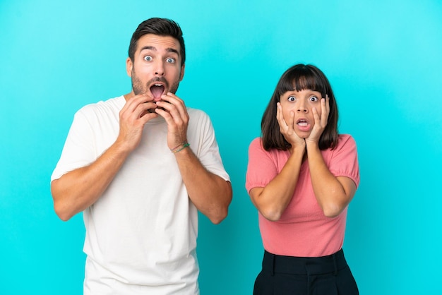 Young couple isolated on blue background surprised and shocked while looking right