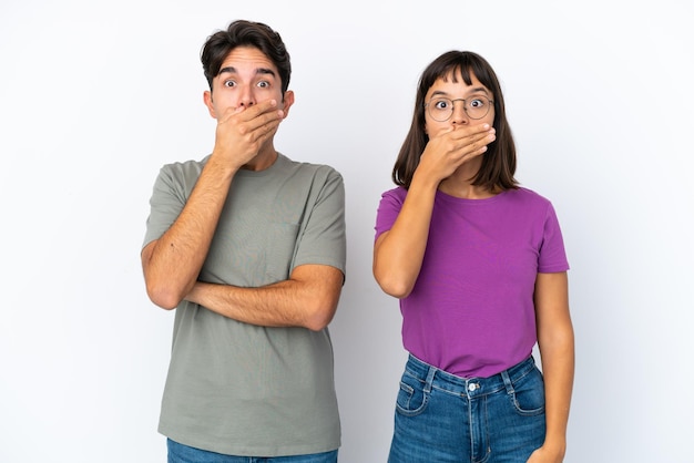 Giovane coppia isolata su sfondo bianco isolato che copre la bocca con le mani per dire qualcosa di inappropriato