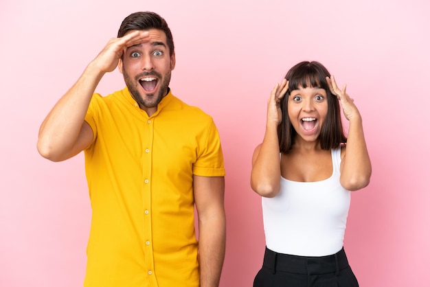 Young couple isolated on pink background has just realized something and has intending the solution