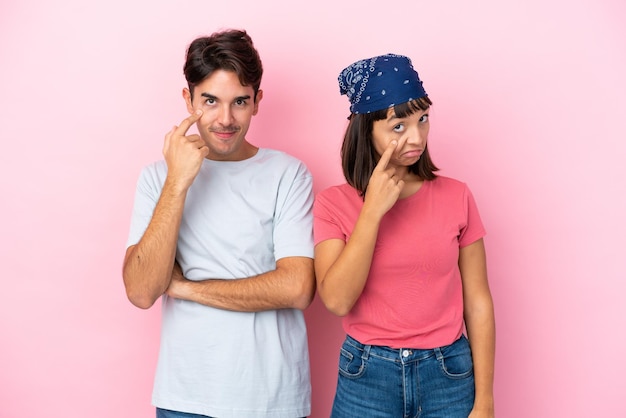 Young couple isolated on pink background looking to the front