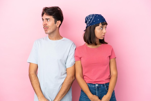 Young couple isolated on pink background nervous and scared