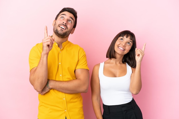 Young couple isolated on pink background pointing a great idea and looking up