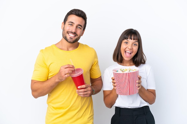 Young couple isolated on white background holding a big bucket of popcorns