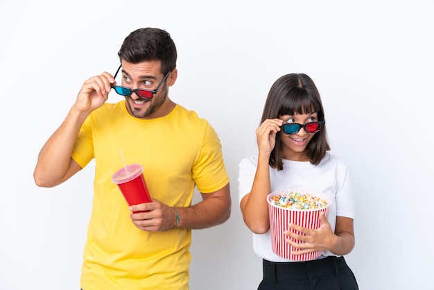 Young couple isolated on white background with 3d glasses and holding a big bucket of popcorns