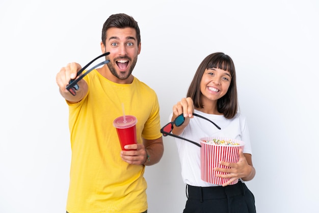 Young couple isolated on white background with 3d glasses and holding a big bucket of popcorns