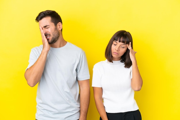Young couple isolated on yellow background unhappy and frustrated with something