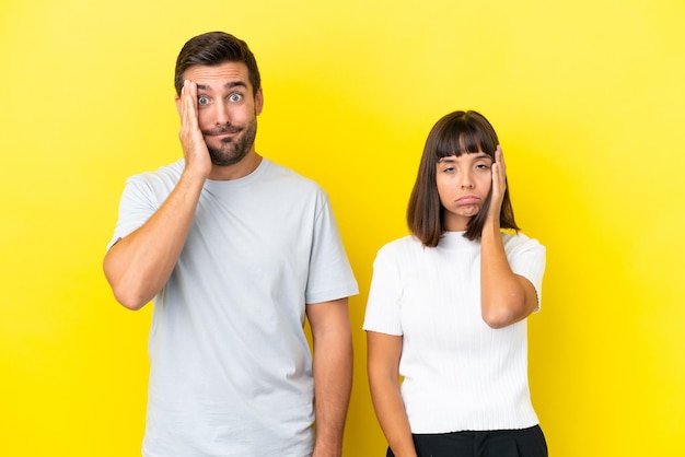 Young couple isolated on yellow background with surprise and shocked facial expression