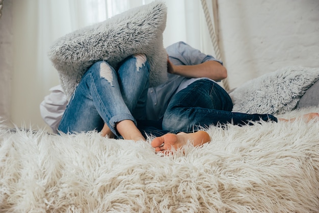 Una giovane coppia in jeans su un letto bianco