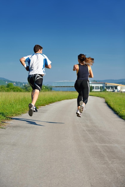 朝の公園でジョギングをしている若いカップル。健康とフィットネスのコンセプト