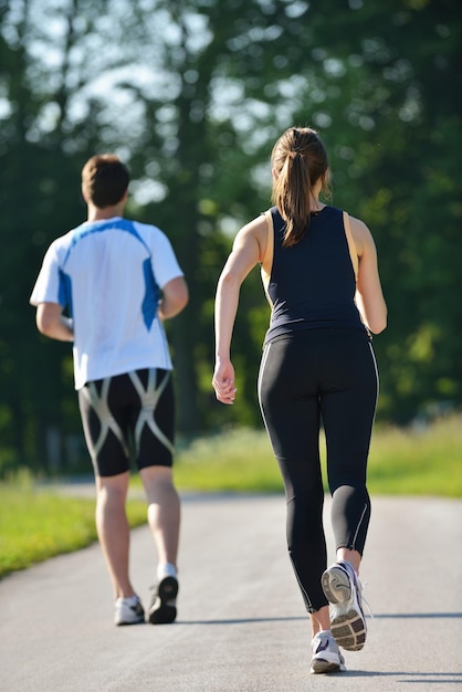 朝の公園でジョギングをしている若いカップル。健康とフィットネスのコンセプト