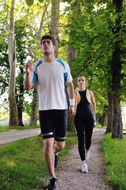 朝の公園でジョギングをしている若いカップル。健康と運動。