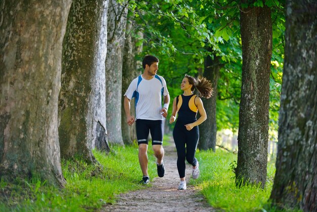 朝の公園でジョギングをしている若いカップル。健康と運動。