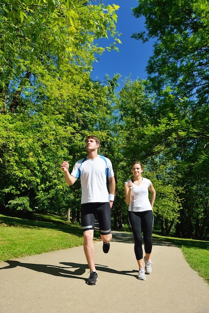 朝の公園でジョギングをしている若いカップル。健康と運動。