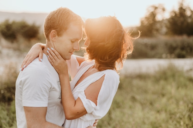 Young couple kissing and huging outdoors in summer.