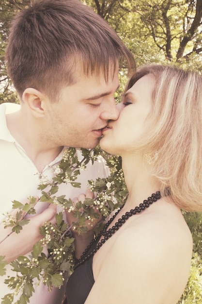 Young couple kissing near the blooming hawthorn