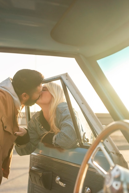 Foto giovani coppie che baciano attraverso il finestrino dell'auto