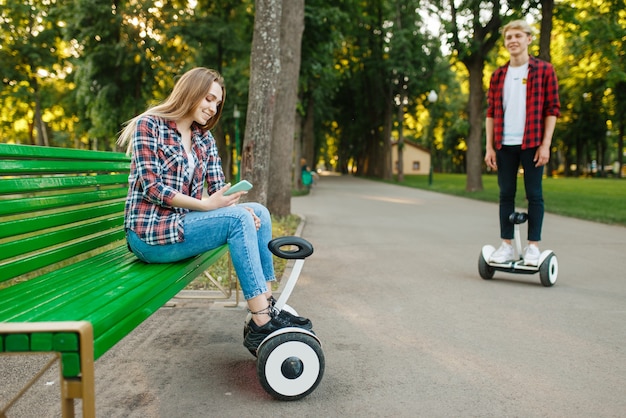 Young couple leisures with gyro board in summer park.