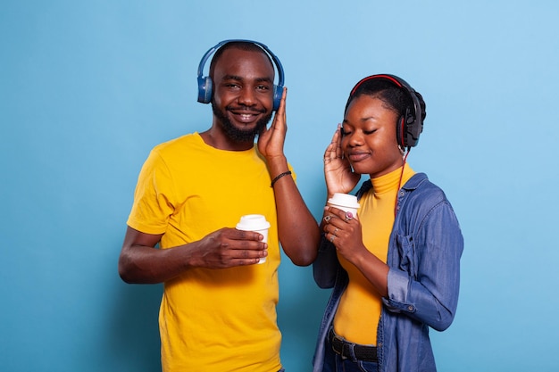 Young couple listening to music playlist on headphones, enjoying song on headset. Man and woman in relationship having fun with audio on online radio, using earphones accessories.