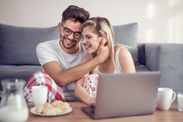 Young couple in living room using laptop