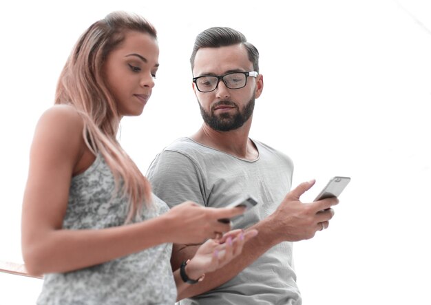 Young couple looking at the screens of their smartphones photo with copy space